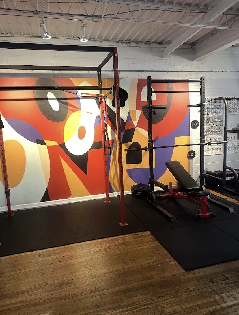 Squat racks and benches in front of the mural wall